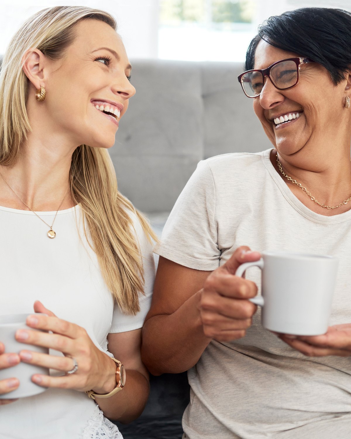 Two women in warm conversation, soft natural light, neutral background